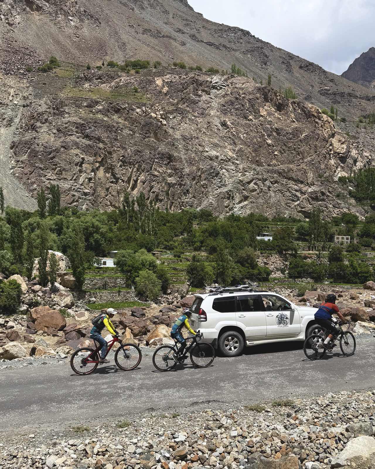 Three riders and the Prado on the valley road beneath the cliffs