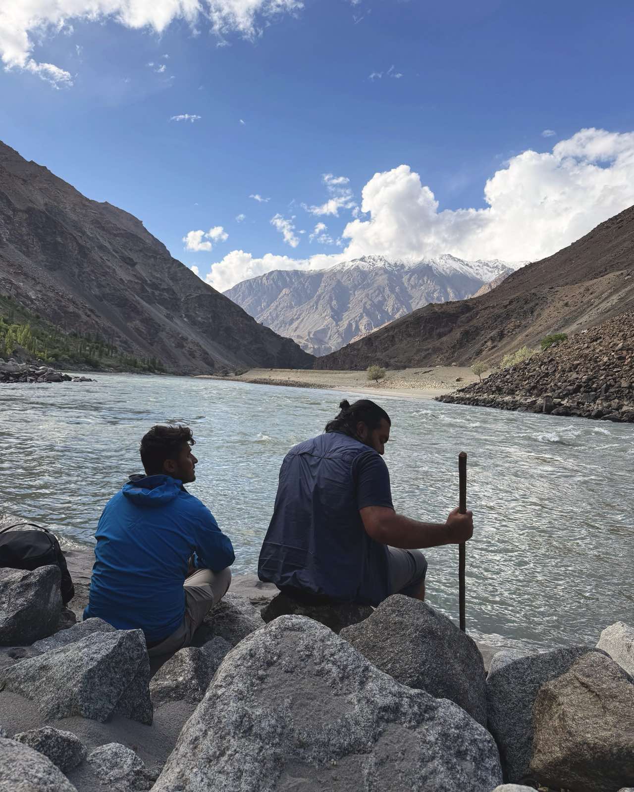The two founders sitting together on the rocks by the river