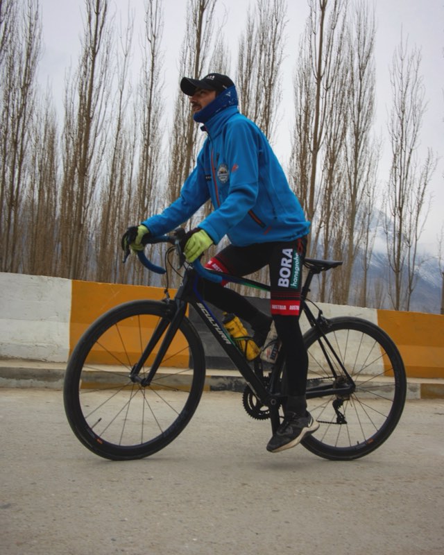 Ejju rolling past the poplars on his road bike