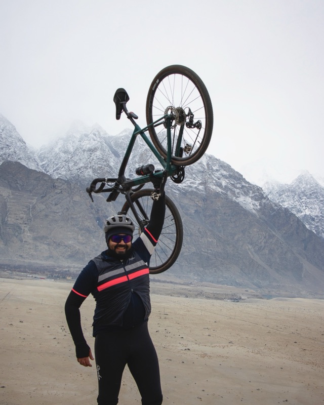 Numaan lifting his bike overhead in the Sarfaranga cold desert