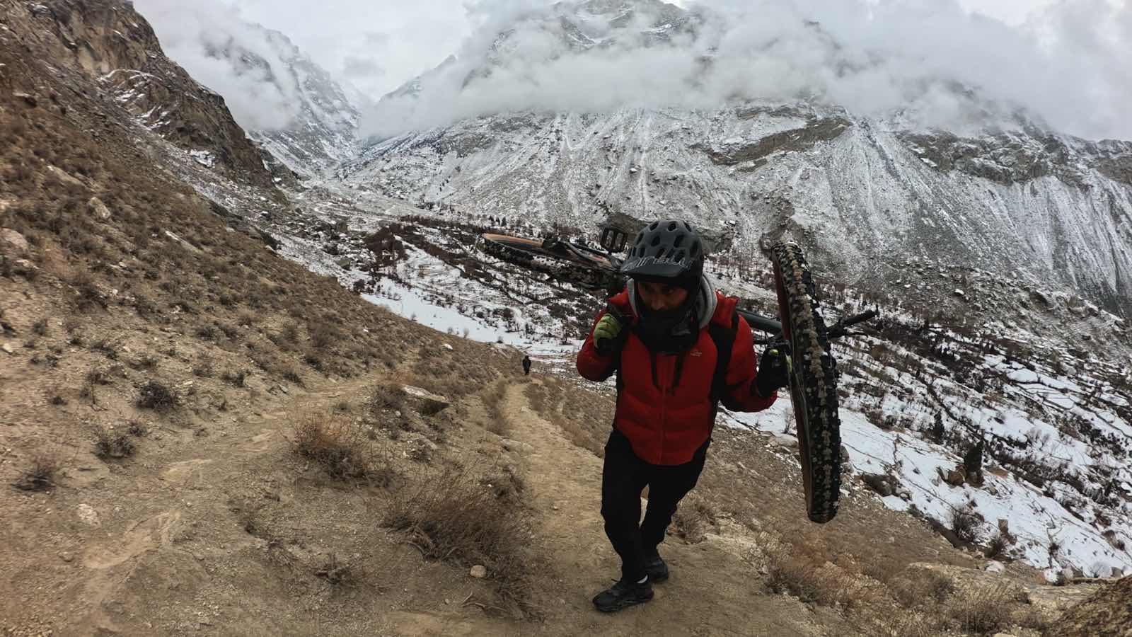 Hassnain carrying his bike up Masrur Rock